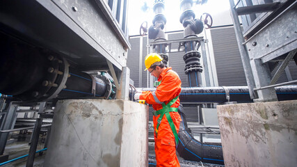 Worker conducts maintenance at industrial facility during daytime operations in urban setting
