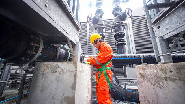 Worker conducts maintenance at industrial facility during daytime operations in urban setting