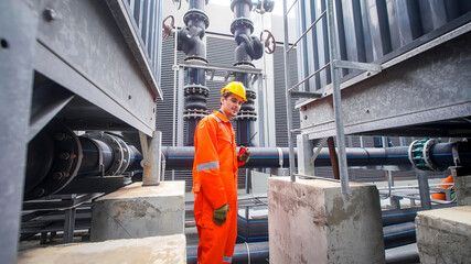 Worker in safety gear conducts maintenance in an industrial facility during daylight hours