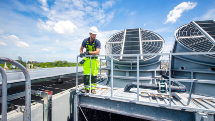 Worker conducts maintenance on rooftop cooling equipment during sunny day