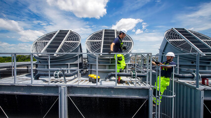 Technicians conducting maintenance on cooling towers at a commercial facility during the day