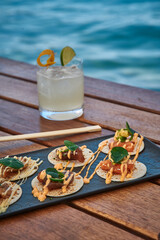 A Tantalizing Spread of Gourmet Tacos Next to a Refreshing Drink by the Shore, Perfectly Capturing the Essence of Coastal Dining Experience