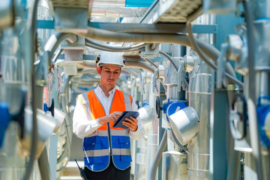 Engineer conducts inspections in an industrial facility while using a tablet for data recording