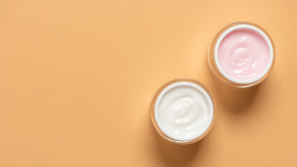 Pink and white cosmetic creams in jars on yellow pastel background, top view, moisturizing cream for face or body