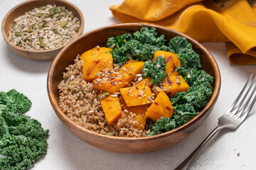 Autumn Harvest Bowl with Quinoa, Green Buckwheat, Roasted Pumpkin, and Kale in Wooden Bowl on Light Background. Healthy Vegan Fall Meal