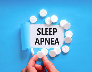Sleep apnea symbol. Concept words Sleep apnea on beautiful white paper. White pills tablets. Doctor's hand. Beautiful blue background. Medical healthy lifestyle sleep apnea concept.
