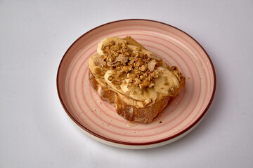 Delicious Toast Topped with Sliced Bananas, Creamy Peanut Butter, and Crunchy Granola on a Stylish Plate