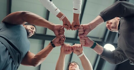 People, fitness and fist bump with team below for unity, solidarity or active mission in gym. Low angle, group or community with hands together in huddle for synergy, cohesion or trust in health club
