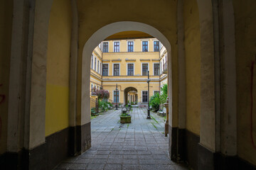 Fototapeta premium Historic courtyard viewed through arched entrance passageway. Nagykanizsa, Hungary.