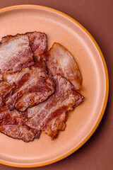 Cooked fried crispy bacon as an ingredient of a delicious English breakfast. Pieces of fried bacon