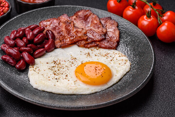 Fried egg, bacon and beans, a classic British breakfast with tomatoes. Egg, bacon and beans