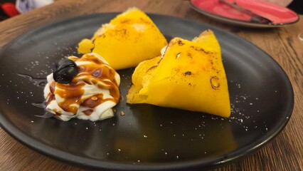 Chestnut pancakes with whipped cream. Filloas or frixuelos. Typical dessert of Galicia and Asturias (Spain). Delicious grilled dessert with cream and caramel drizzle on black plate