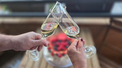 Celebration toast with champagne glasses over festive cake. Cake Pavlova and two glasses of champagne. Happy birthday