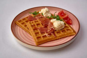 Deliciously Served Waffles Topped with Cream, Aged Ham, Fresh Greens, and Juicy Tomatoes for a Perfect Culinary Experience