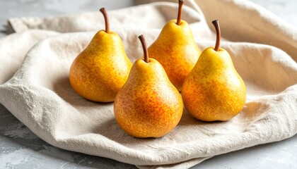 Four fresh yellow pears on a linen cloth