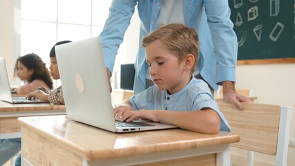 Caucasian teacher helping energetic boy coding engineering prompt while diverse student using software generated AI. Children sitting and programing system. Cute student learning about code. Pedagogy.