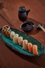 A Colorful Assortment of Fresh Sushi on a Elegant Blue Plate with Soy Sauce and Chopsticks Ready for Indulgence and Culinary Delight Experience