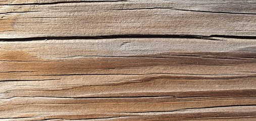 A close-up of weathered wooden planks with faded gray and warm brown tones, natural cracks, and knot shadows. The rough, aged surface creates a rustic, organic wood texture background