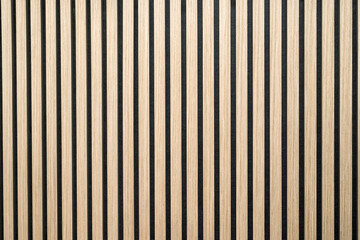 Decorative interior wall with vertical wooden slats or strips over black background. Contemporary architectural wood panel texture ideal for design, background, or pattern use