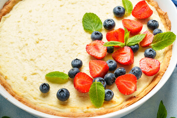 Tart with cheese and fresh berries on blue background.