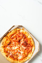 Pizza Margarita in a cardboard box on white background.