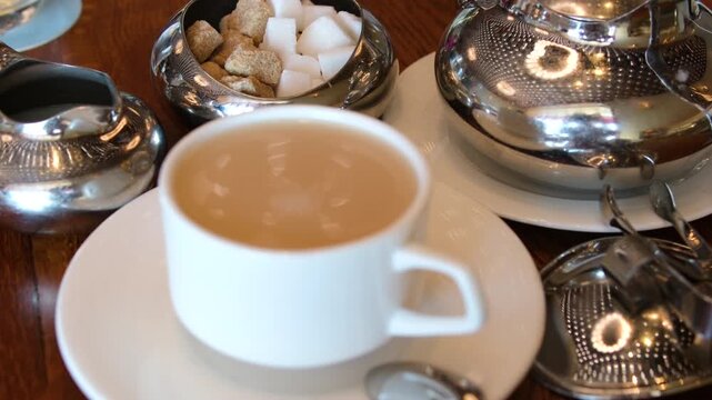 Teh Poci, traditional Javanese jasmine tea from Central Java, served in a floral porcelain cup with rock sugar and clay teapot. A spoon adds sugar in this cozy Indonesian tea ritual. . High quality 4k