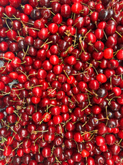 Fresh cherries with stems close-up, piled together. Image suitable for food blogs, food content, agricultural marketing and healthy