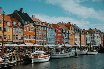 Naklejka premium Les maisons colorées sur les rives du canal Nyhavn, au cœur de la ville de Copenhague au Danemark, avec des bateaux