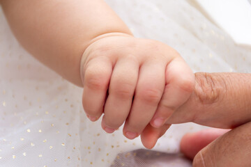 Baby girl holding father finger.