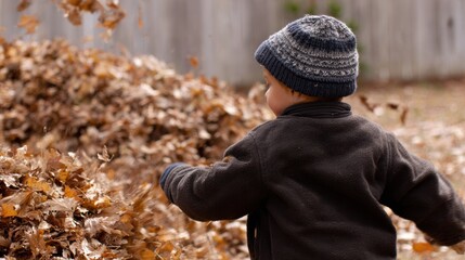 Fototapeta premium A child playfully revels in the rustic beauty of autumn, flinging a cascade of vibrant leaves into the crisp air, showcasing the joy of childhood in a natural outdoor setting.