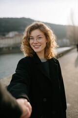 Obraz premium Happy young caucasian female with curly hair enjoys riverfront walk