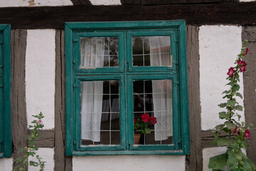 Stare zabudowania, domy szachulcowe z elementami roślinnymi, kwiatami i drzewkami.  © Magdalena