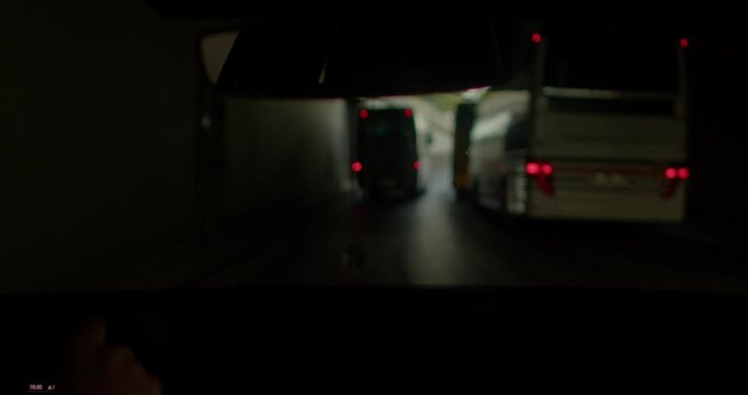 A driver on a foggy highway checks the rear view mirror, spotting passing vehicles like a bus in a tunnel. The fog enhances the tension