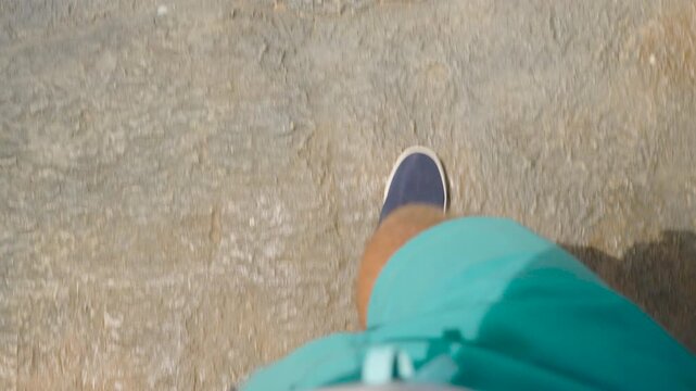 Man Walking on Large Rock Surface in Blue Shorts and Blue Shoes With Shadow Visible From First Person Angle at Overlap Stone Samui, Adventure Exploration Concept