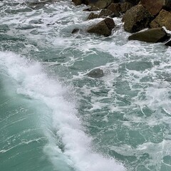 Dramatic ocean waves crashing with explosive white spray and foam against rocks, creating powerful water dynamics with green sea water and spectacular wave action