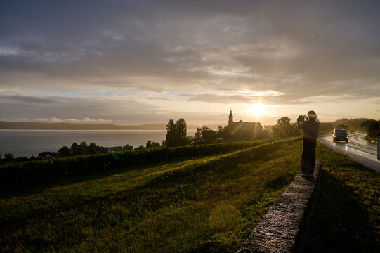 woman taking picture of the sunst over the bodensee