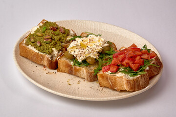 Delicious Trio of Artisan Toasts Featuring Fresh Toppings Like Avocado, Cream Cheese, and Tomato on Toasted Bread Slices Delightfully Served on a Plate