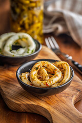 Marinated squid rings in bowl on wooden table.