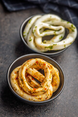 Marinated squid rings in bowl on black table.