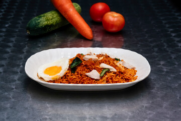Spicy Maggi Mee Goreng with Chicken, Fried Egg, and Vegetables in plate isolated on dark background side view of Malaysian food