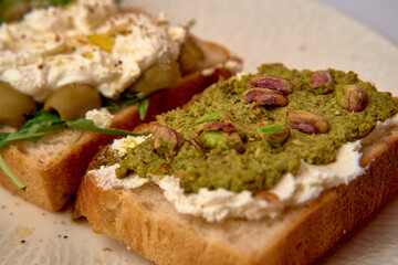 Deliciously Crafted Bread Toppings Featuring Savory Green Pesto and Creamy Cheese Spread with Tantalizing Pistachios and Fresh Ingredients