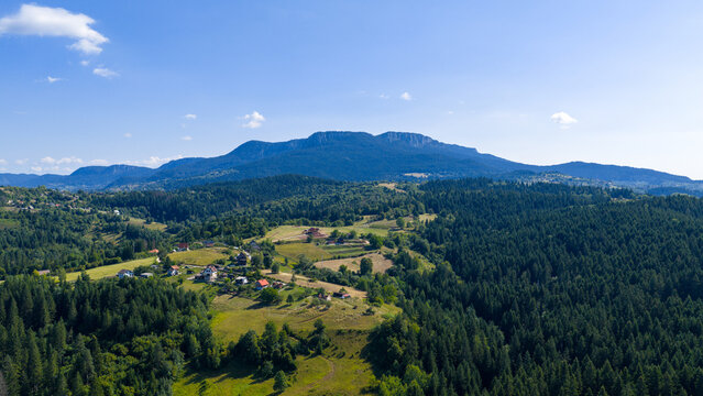 Drone photo of a wide forested Romanija mountain with rocky ridges and rural clearings under a bright blue sky