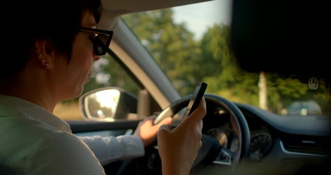 This video shows a woman driving while using her cell phone, highlighting the distractions of modern technology and reflecting on road safety