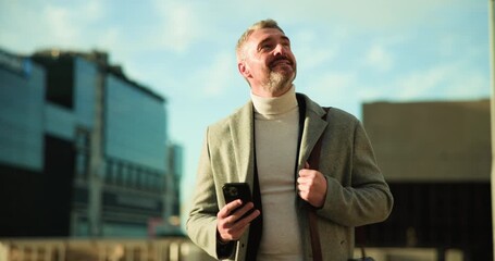 Phone, smile and walking with businessman in city to check agenda or schedule for travel. App, communication and thinking with happy mature employee outdoor in urban town for commute to work - Powered by Adobe