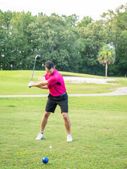 White male golfer in his 40s chipping the ball.