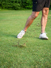 Golfer chipping ball with dirt flying through the air