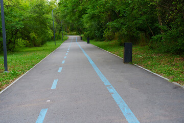 Empty park pathway leads through lush greenery for recreational activities on a bright day