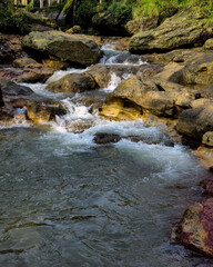 A natural scene of a rushing stream flowing over large, smooth rocks.