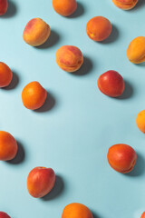 Scattered fresh apricots on pastel blue background. Minimalist summer concept with vibrant colors. Ideal for themes of health, nature, food, freshness, and organic lifestyle.
