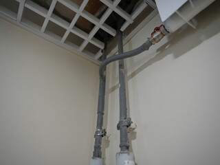 Close-up view of heating system pipes connected to a radiator under a suspended ceiling in a...